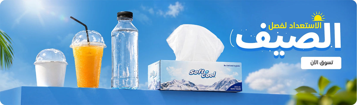 Get Ready for Summer banner featuring Soft & Cool white tissues box alongside disposable clear dome cups and a water bottle displayed on a blue platform against a bright summer sky background with Shop Now call to action. | بانر الاستعداد لفصل الصيف يعرض علبة مناديل سوفت آند كول البيضاء مع أكواب شفافة ذات غطاء قبة وزجاجة ماء معروضة على منصة زرقاء بخلفية سماء صيفية مشرقة مع زر تسوق الآن.