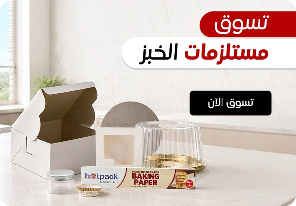 Shop Baking Essentials banner featuring Hotpack parchment baking paper roll, clear plastic dome cake container, white bakery box with window, mini aluminium cupcake liners, and small clear plastic jar displayed on a marble kitchen countertop with Shop Now call to action. | بانر تسوق مستلزمات الخبز يعرض رول ورق خبز هوت باك، علبة كيك بلاستيكية شفافة بغطاء قبة، علبة مخبوزات بيضاء مع نافذة، كبسولات ألومنيوم صغيرة للكب كيك، وجرة بلاستيكية شفافة صغيرة معروضة على طاولة مطبخ رخامية مع زر تسوق الآن.