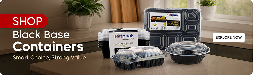 Shop Black Base Containers banner featuring Hotpack Classique Range disposable containers including 6-compartment black base container with lid, round black container with clear lid, and multi-compartment black container with clear dome lid on a kitchen countertop with Explore Now call to action. | بانر تسوق الحاويات ذات القاعدة السوداء يعرض حاويات هوت باك كلاسيك رينج تشمل حاوية 6 أقسام مع غطاء، حاوية دائرية سوداء مع غطاء شفاف، وحاوية متعددة الأقسام مع غطاء قبة شفاف على طاولة مطبخ مع زر تصفح الآن.