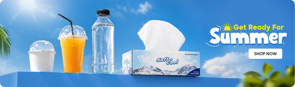 Get Ready for Summer banner featuring Soft & Cool white tissues box alongside disposable clear dome cups and a water bottle displayed on a blue platform against a bright summer sky background with Shop Now call to action. | بانر الاستعداد لفصل الصيف يعرض علبة مناديل سوفت آند كول البيضاء مع أكواب شفافة ذات غطاء قبة وزجاجة ماء معروضة على منصة زرقاء بخلفية سماء صيفية مشرقة مع زر تسوق الآن.