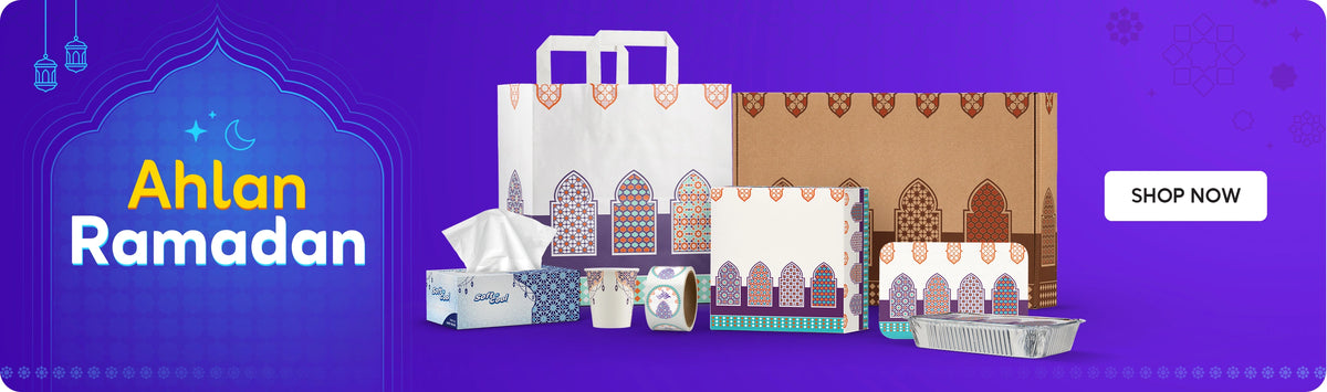 Ramadan packaging and tissues banner featuring decorative paper bags, gift boxes, Soft n Cool tissue box, printed paper cups, tape roll and aluminum foil tray with Ahlan Ramadan message on a purple background and Shop Now call to action. بانر مستلزمات تغليف ومناديل رمضان يعرض أكياس ورقية مزخرفة، علب هدايا، علبة مناديل سوفت آند كول، أكواب ورقية مطبوعة، رول لاصق وصينية ألمنيوم مع عبارة أهلًا رمضان على خلفية بنفسجية وزر تسوق الآن.