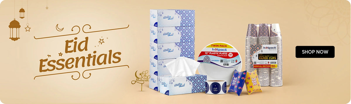 Eid Essentials banner featuring Soft & Cool facial tissue boxes with Eid edition design, Hotpack 10" plastic plates twin pack, Hotpack heavy duty paper cups special edition 150-pack, and Eid gift wrap accessories displayed on a warm beige background with Ramadan lanterns and Eid Mubarak calligraphy with Shop Now call to action. | بانر مستلزمات العيد يعرض علب مناديل سوفت آند كول بتصميم عيد مميز، طبق بلاستيك هوت باك 10 إنش توين باك، أكواب ورقية هوت باك هيفي ديوتي إصدار خاص 150 كوب، وإكسسوارات تغليف هدايا العيد معروضة على خلفية بيج دافئة مع فوانيس رمضانية وخط عيد مبارك مع زر تسوق الآن.