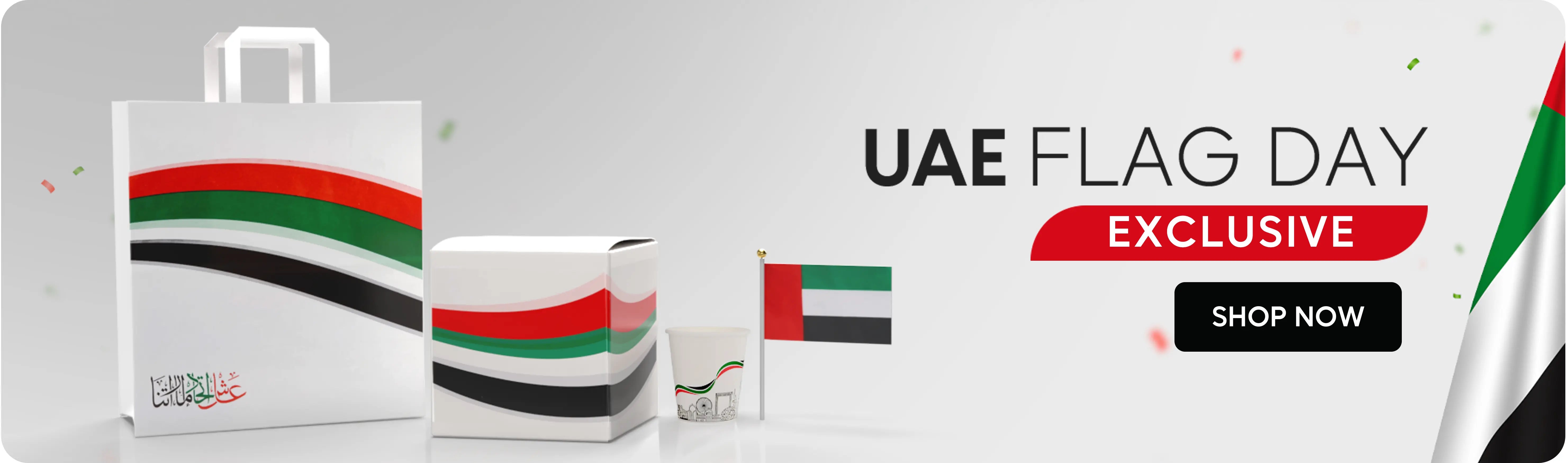 UAE Flag Day exclusive offer – white and grey banner featuring UAE flag-themed products (bag, box, cup, and small flag) with a “Shop Now” button. عرض خاص ليوم العلم الإماراتي – لافتة باللونين الأبيض والرمادي تحتوي على منتجات مزينة بألوان علم الإمارات (حقيبة، صندوق، كوب، وعلم صغير) مع زر 