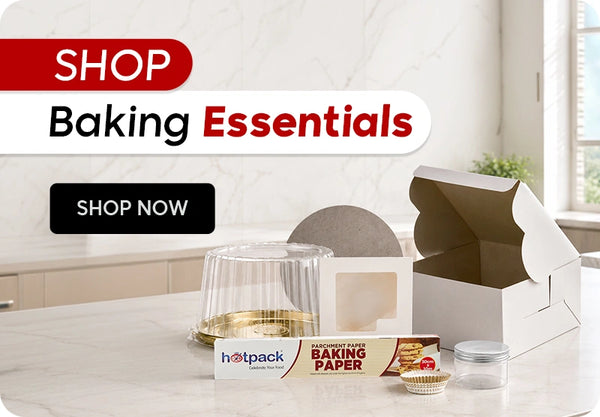Shop Baking Essentials banner featuring Hotpack parchment baking paper roll, clear plastic dome cake container, white bakery box with window, mini aluminium cupcake liners, and small clear plastic jar displayed on a marble kitchen countertop with Shop Now call to action. | بانر تسوق مستلزمات الخبز يعرض رول ورق خبز هوت باك، علبة كيك بلاستيكية شفافة بغطاء قبة، علبة مخبوزات بيضاء مع نافذة، كبسولات ألومنيوم صغيرة للكب كيك، وجرة بلاستيكية شفافة صغيرة معروضة على طاولة مطبخ رخامية مع زر تسوق الآن.